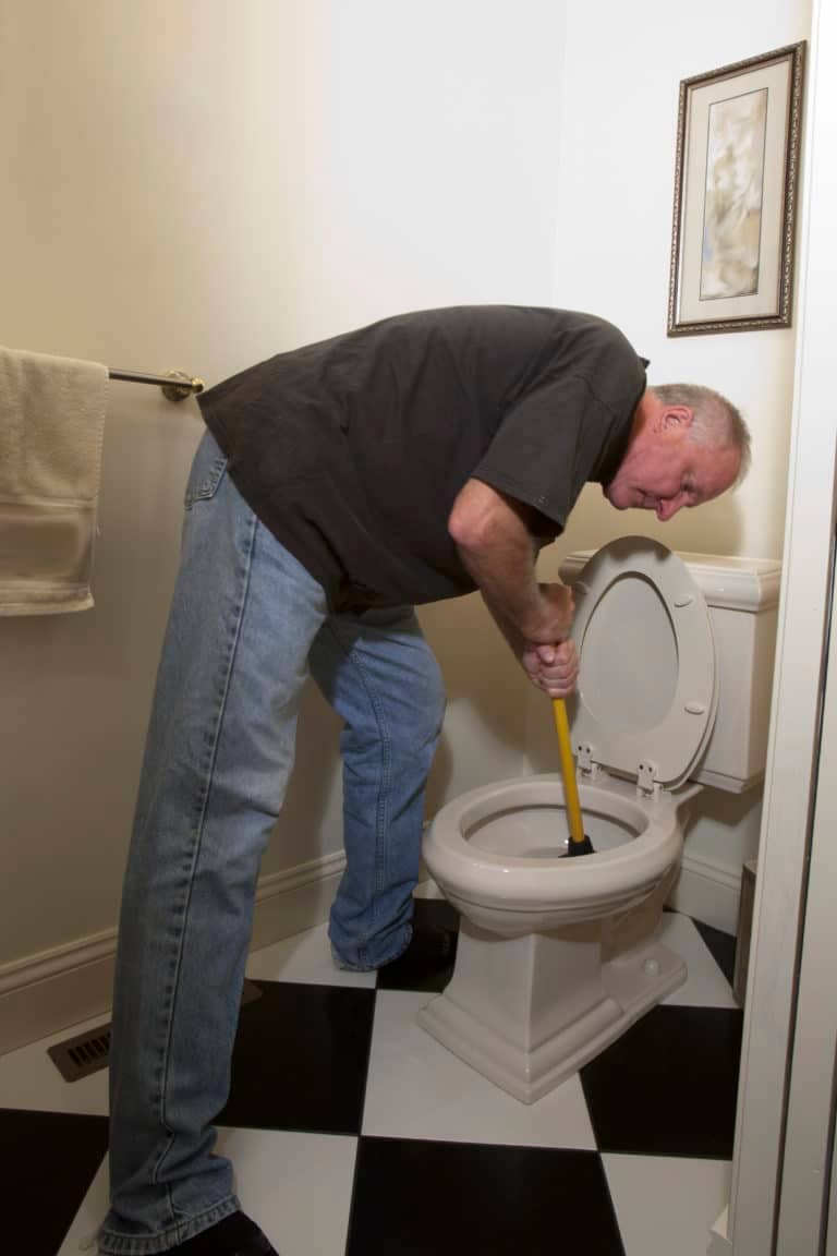 Man in with plunger fixing blocked toiler