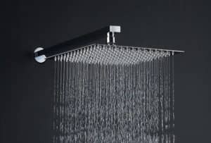 A modern shower head against a dark background, producing a stream of water droplets.