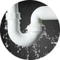 A circular logo featuring a grayscale image of a plumbing pipe with water leaking from its connection points.